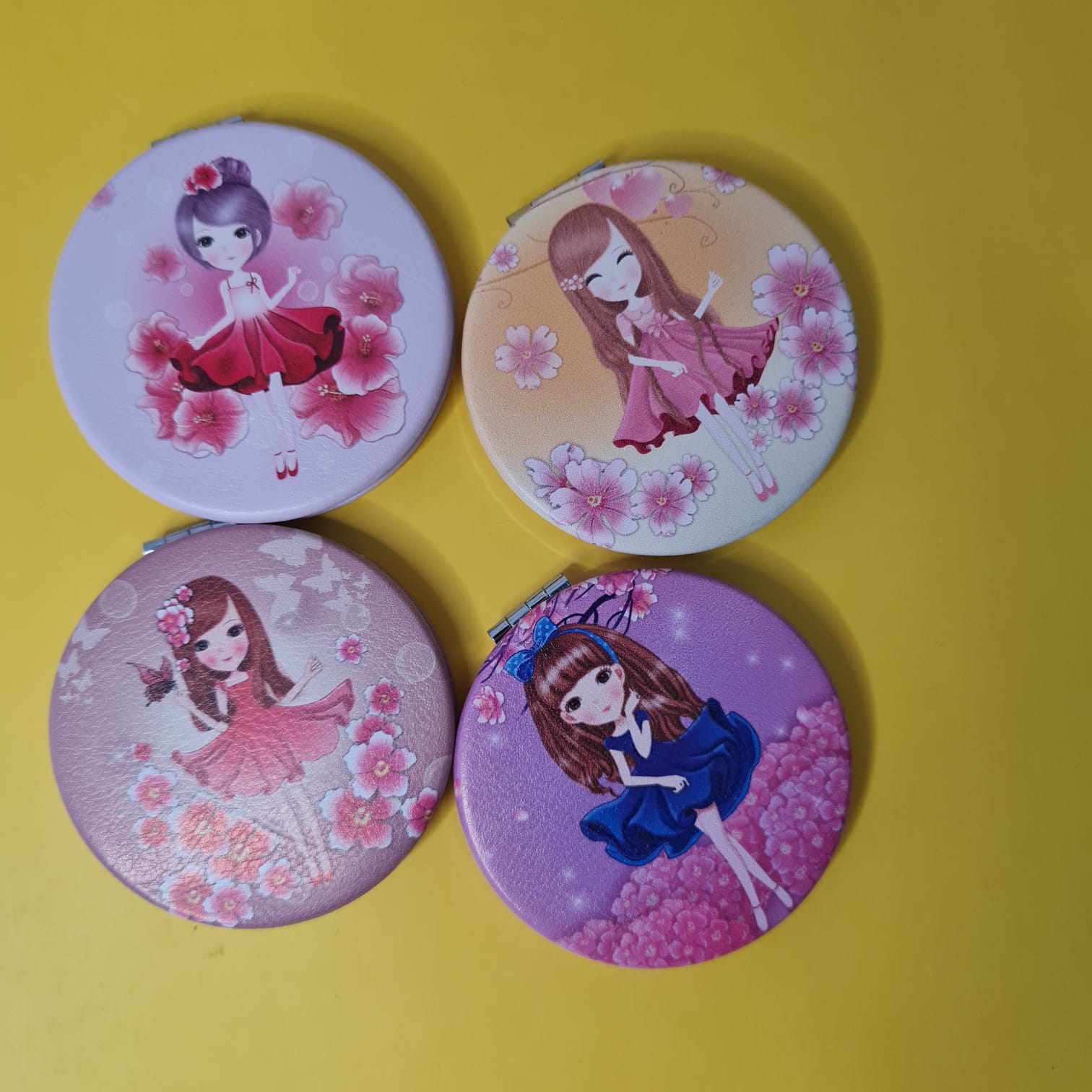 Four round mirrors with cartoon character designs on a yellow background